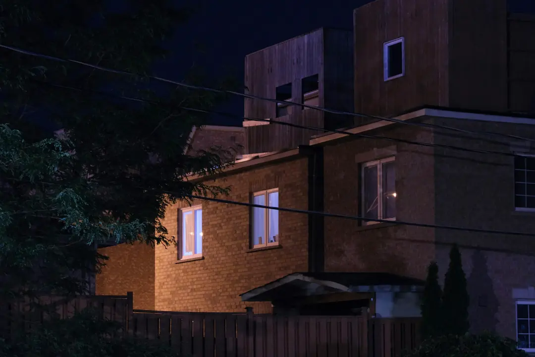 A brick house at night with warm light in its windows